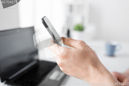 Image of close up of hand with smartphone at office