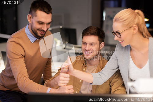 Image of business team making thumbs up gesture at office