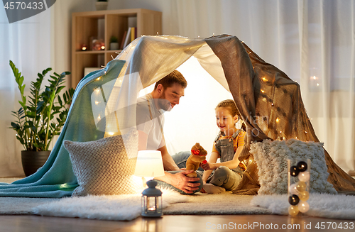 Image of happy family playing with toy in kids tent at home