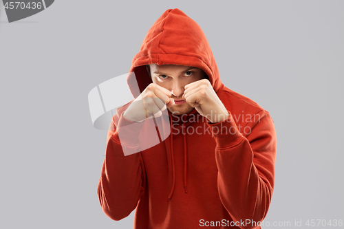 Image of man in red hoodie fighting with fists or boxing