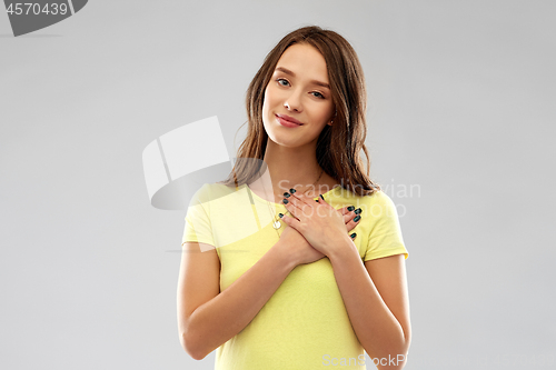 Image of smiling teenage girl holding hands on heart