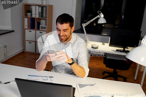 Image of businessman with smartphone and computer at office