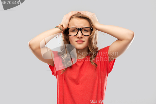 Image of desperate teenage girl in glasses holding to head