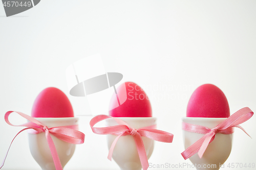 Image of pink easter eggs in holders on white background