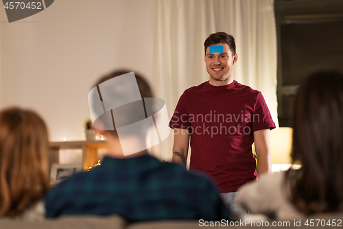 Image of friends playing guessing game at home in evening