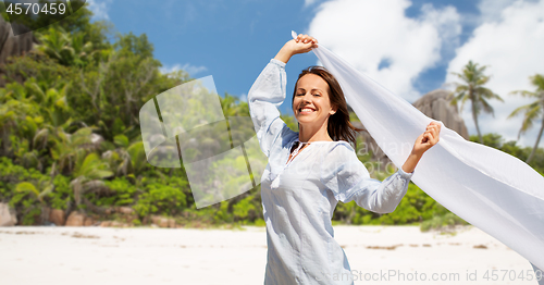 Image of happy woman with shawl waving in wind on beach