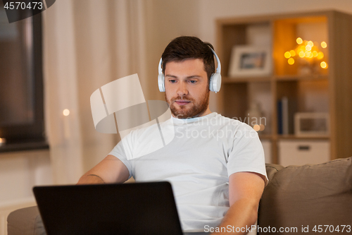 Image of man in headphones with laptop computer at night