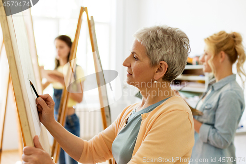 Image of senior woman drawing on easel at art school studio