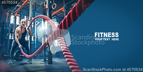 Image of Woman with battle rope battle ropes exercise in the fitness gym.