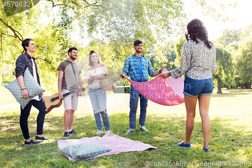 Image of friends arranging place for picnic at summer park