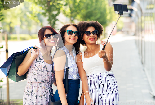 Image of women with shopping bags taking selfie outdoors