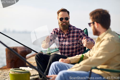 Image of happy male friends with rods talking about fishing