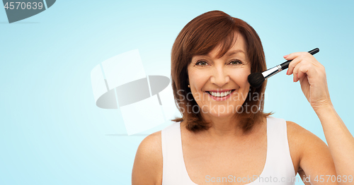 Image of smiling senior woman with make up blush brush