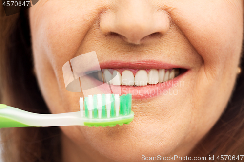 Image of senior woman with toothbrush brushing her teeth