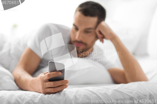 Image of close up of man with smartphone in bed in morning