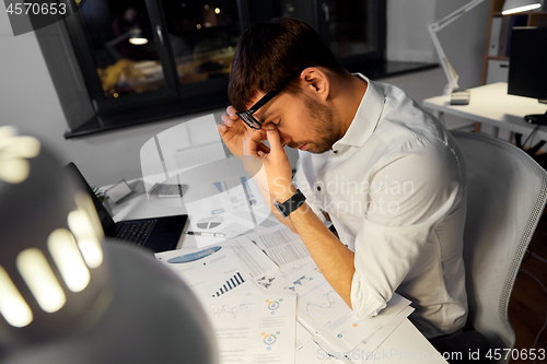 Image of tired businessman working at night office