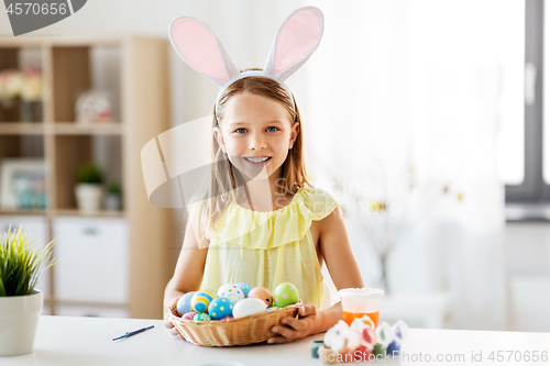 Image of happy girl with colored easter eggs at home