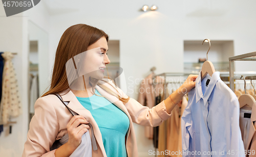 Image of happy woman choosing clothes at clothing store