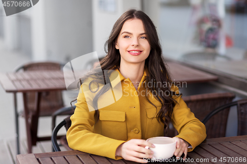 Image of teenage girl drinking hot chocolate at city cafe