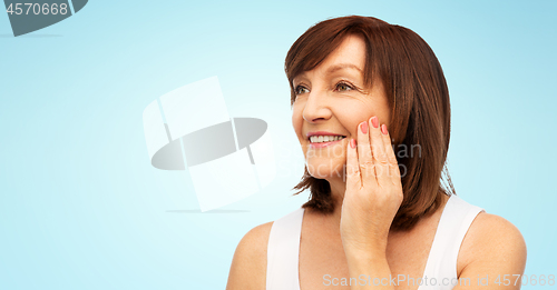 Image of portrait of smiling senior woman touching her face