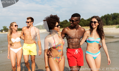 Image of happy friends walking along summer beach