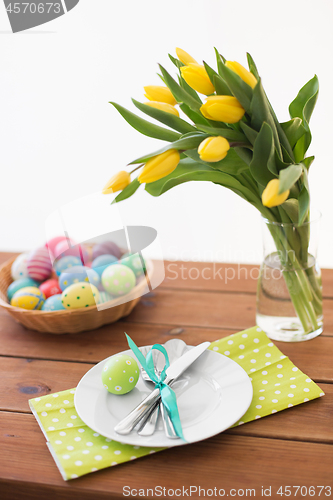 Image of easter eggs in basket, plates, cutlery and flowers