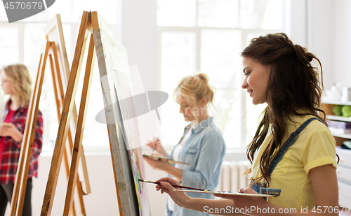 Image of woman with easel painting at art school studio