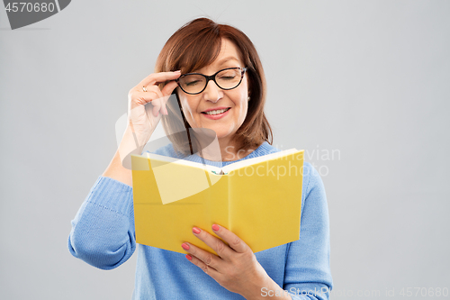 Image of portrait of senior woman in glasses reading book