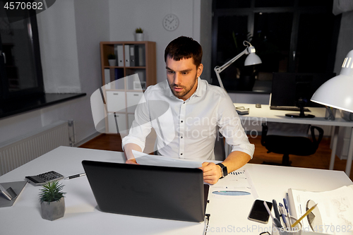 Image of businessman with laptop working at night office