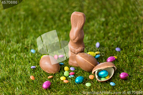 Image of chocolate bunny, eggs and candy drops on grass