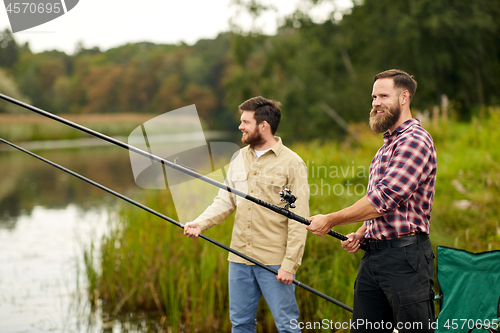 Image of friends with fishing rods at lake or river