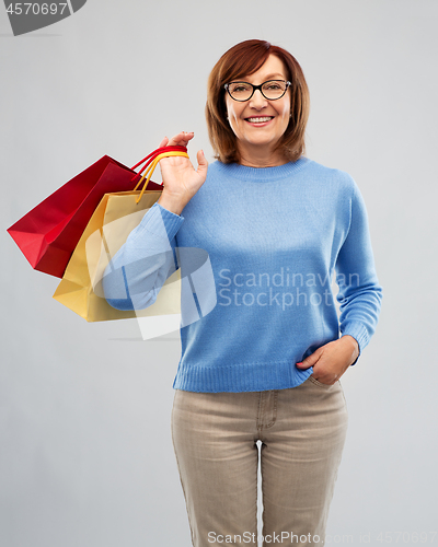Image of senior woman with shopping bags over grey