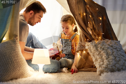 Image of happy family playing with toy in kids tent at home