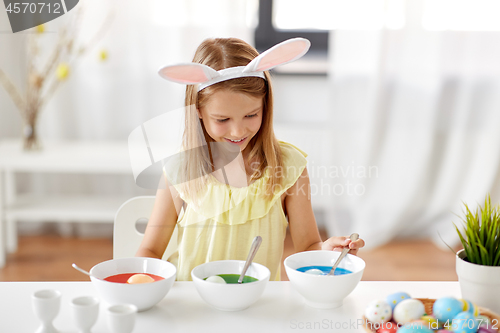 Image of girl coloring easter eggs by liquid dye at home