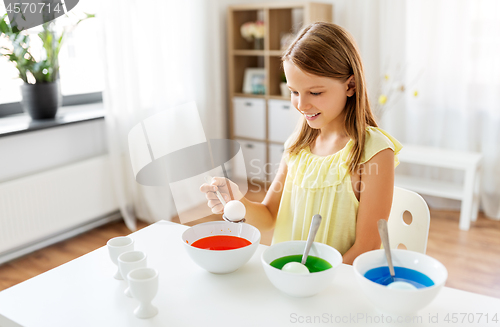 Image of girl coloring easter eggs by liquid dye at home