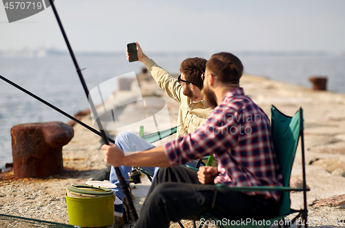 Image of friends fishing and taking selfie by smartphone