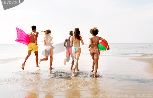 Image of friends run with beach ball and swimming mattress