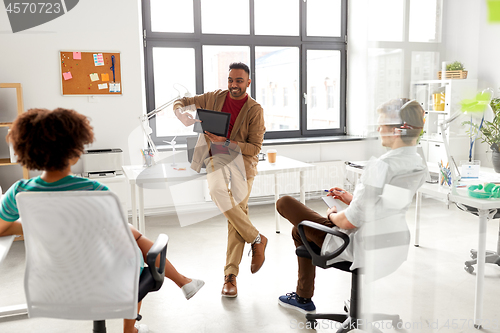 Image of man showing tablet pc to creative team at office