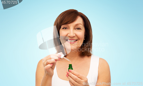 Image of smiling senior woman with bottle of serum