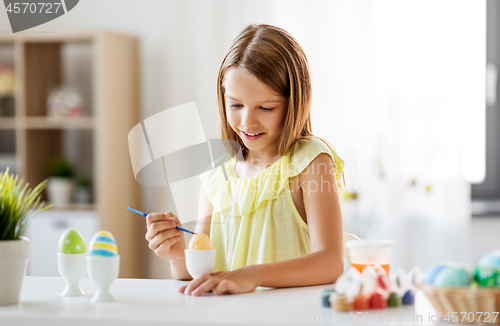 Image of happy girl coloring easter eggs at home