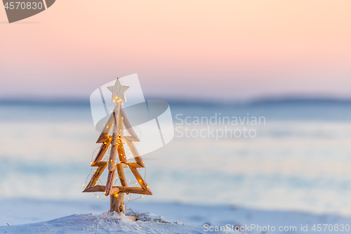 Image of Christmas tree with fairy lights on the beach in summer