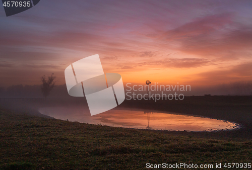 Image of Red skies at dawn with light mist across rural farmlands