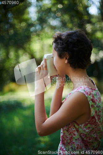 Image of Active girl taking photo on instant camera in sunny forest