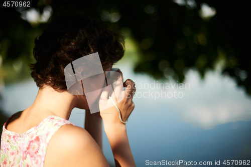 Image of Active girl taking photo on instant camera in sunny forest