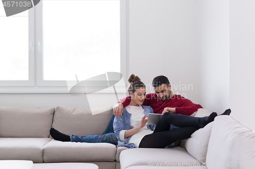 Image of couple relaxing at  home with tablet computers