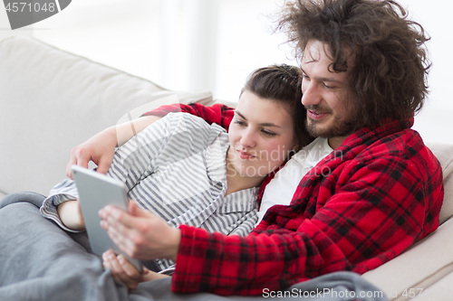 Image of couple relaxing at  home with tablet computers