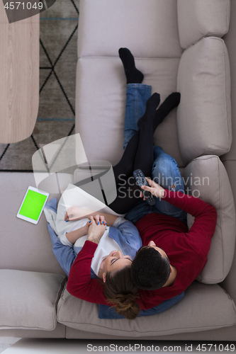 Image of Young couple on the sofa watching television top view