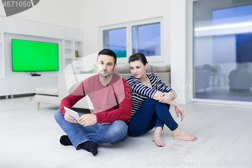 Image of Young Couple using digital tablet on the floor