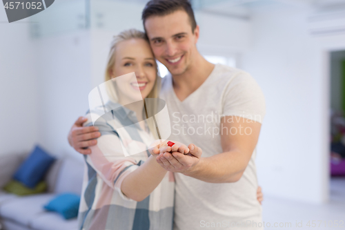 Image of couple showing small red house in hands