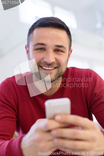 Image of young man using a mobile phone  at home